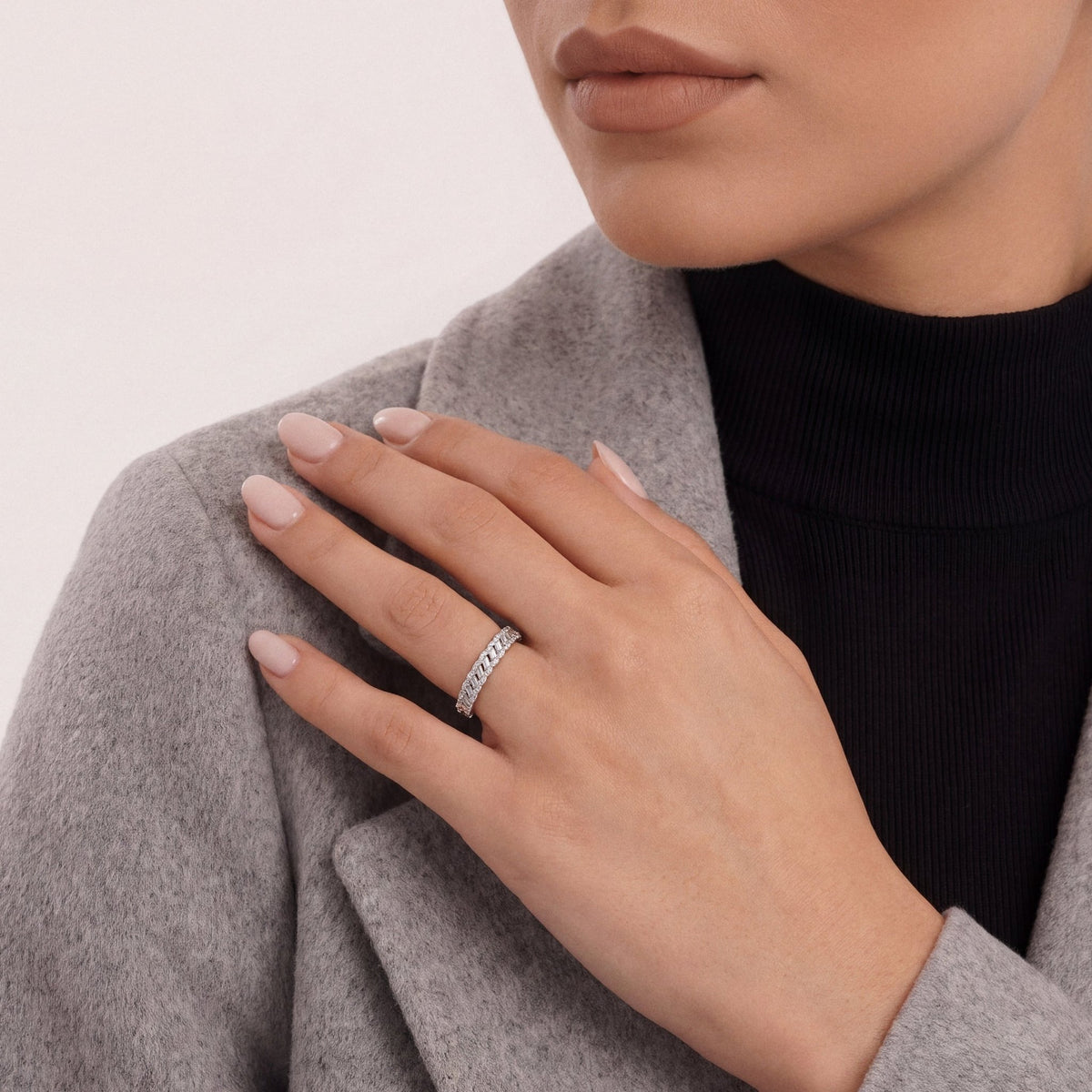 Woman in a grey cashmere coat over a black mock neck wearing a 0.44 ct tw natural diamond braided baguette half eternity ring in 14K white gold