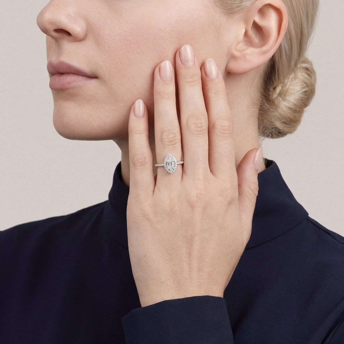 Woman in a midnight-navy funnel-neck top wearing a 0.48 ct tw natural diamond marquise-shaped baguette halo ring in 14K white gold