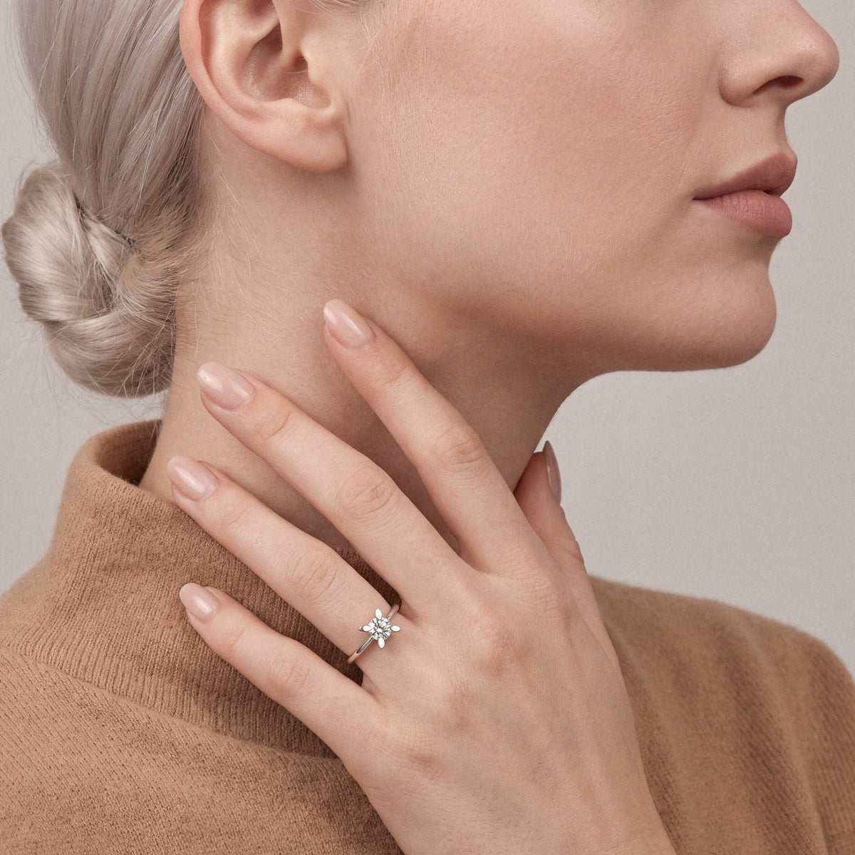 Woman in a camel cashmere turtleneck wearing a 0.60 ct natural diamond four-petal solitaire ring in 14K white gold
