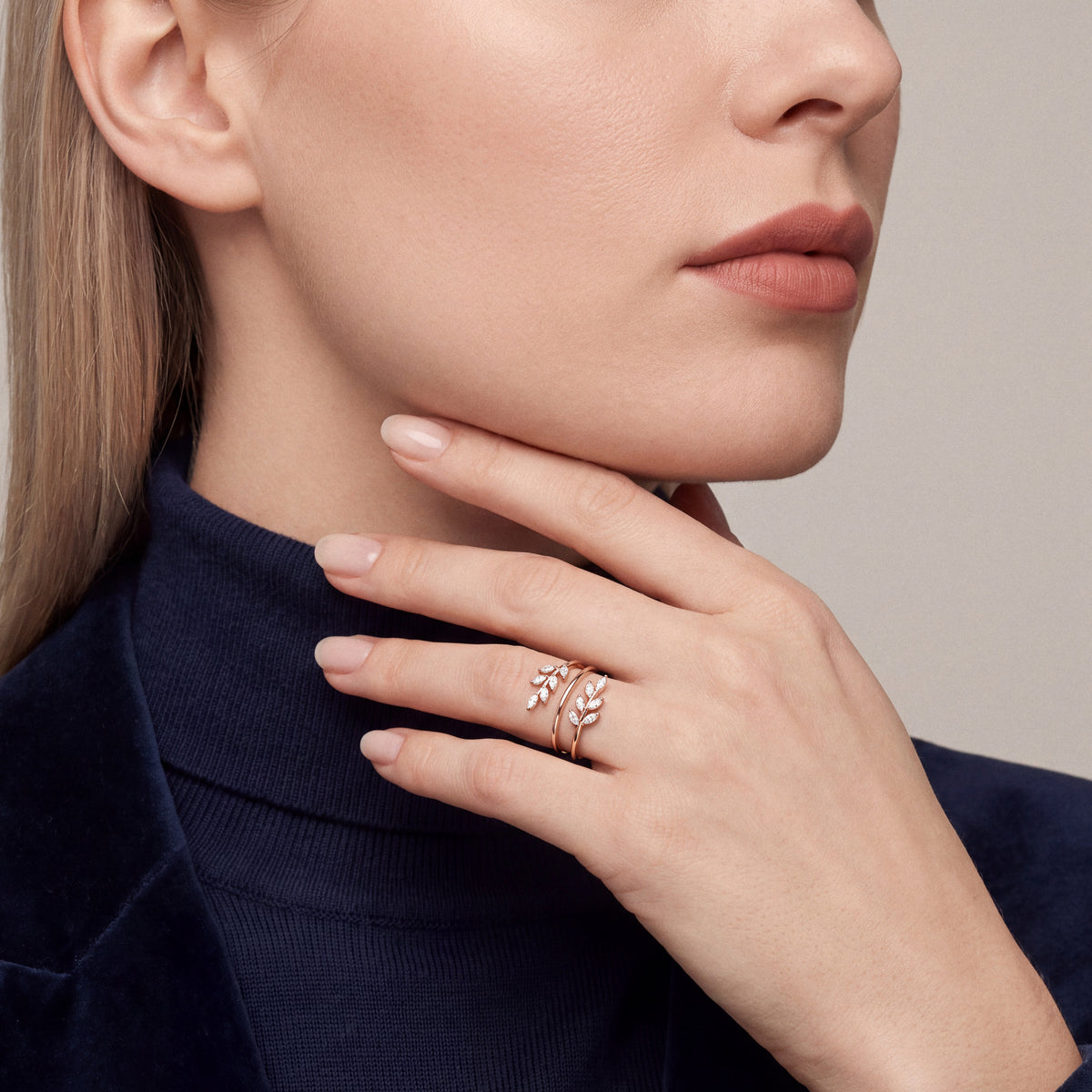 Marquise natural diamond leaf wrap ring in 14K rose gold worn on the ring finger, hand along the jaw over a navy turtleneck