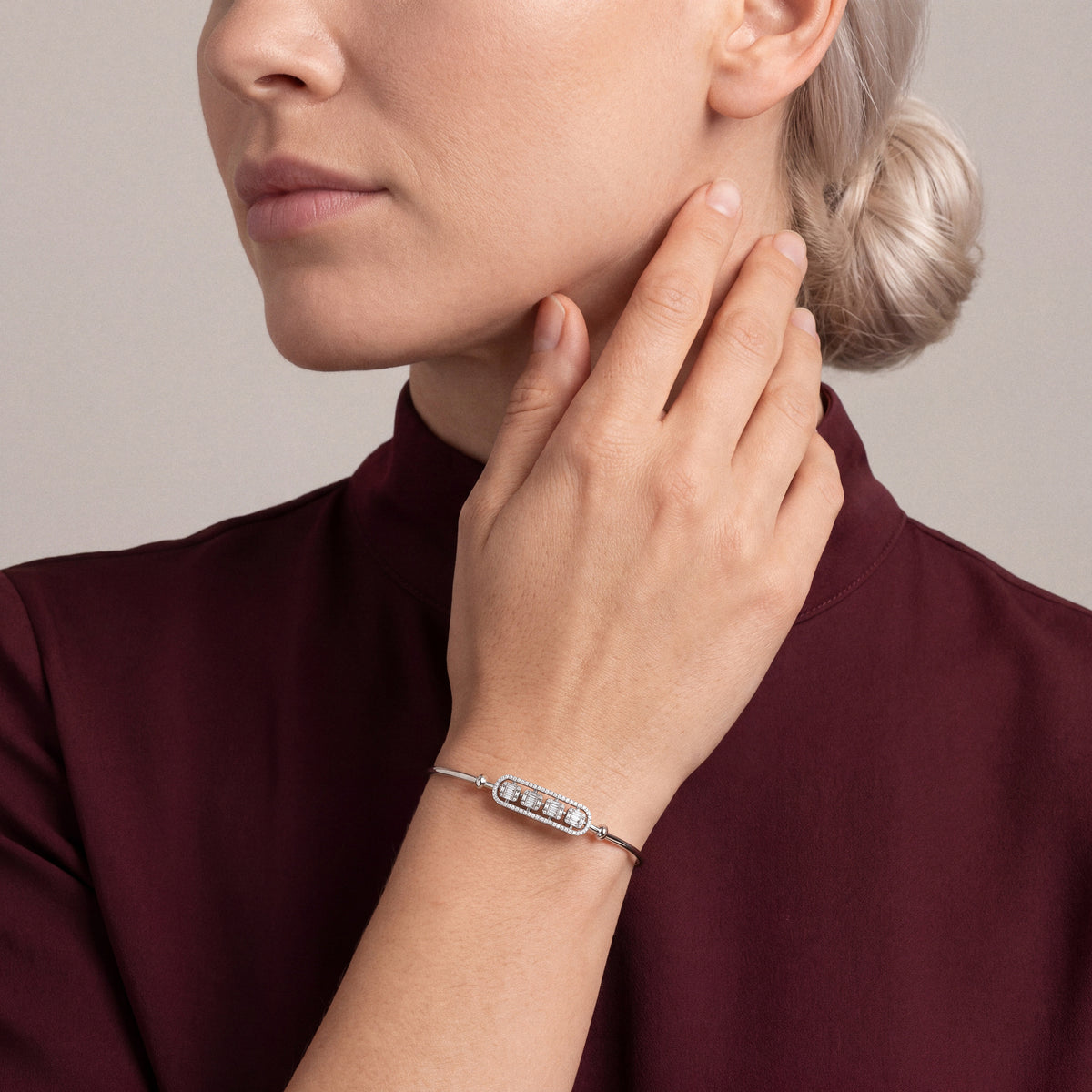 Woman in an oxblood high-neck top wearing a natural diamond baguette bar bangle in 18K white gold