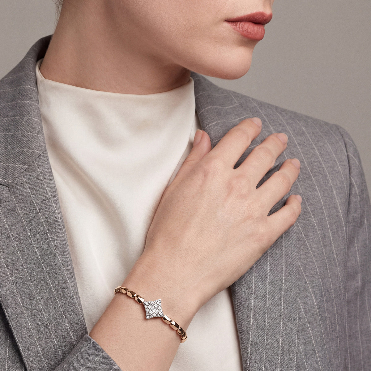 Woman in a grey pinstripe blazer wearing a natural diamond baguette star bracelet in 14K rose and white gold