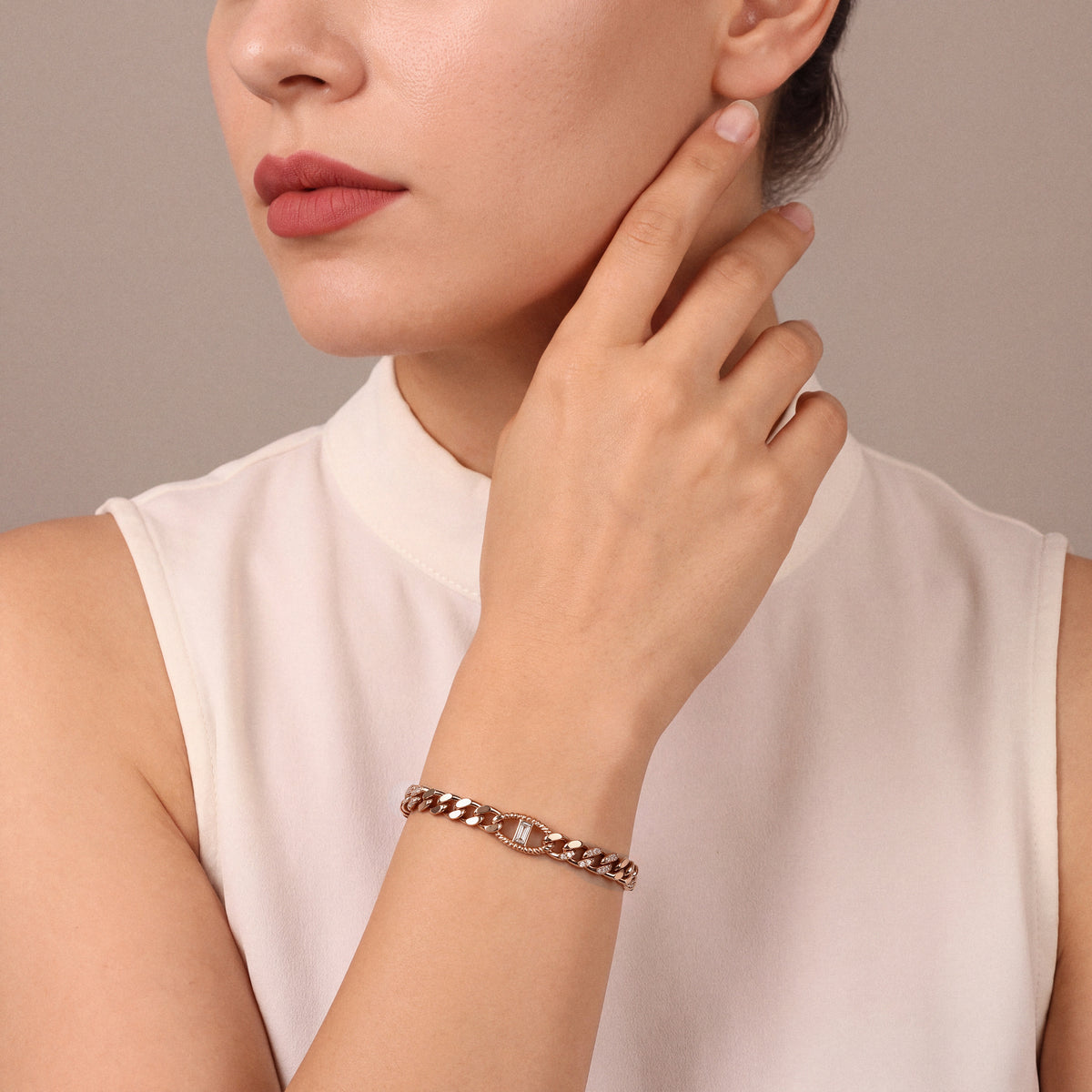Woman in an ivory silk stand-collar top wearing a natural diamond baguette curb chain bracelet in 14K rose gold