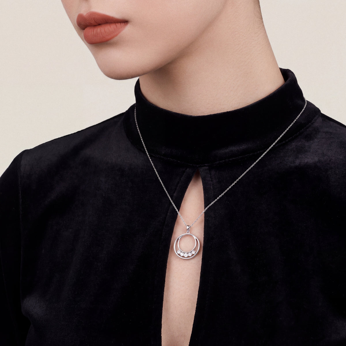 Woman in a black velvet mock-neck top wearing the natural diamond double circle pendant necklace in 14K white gold