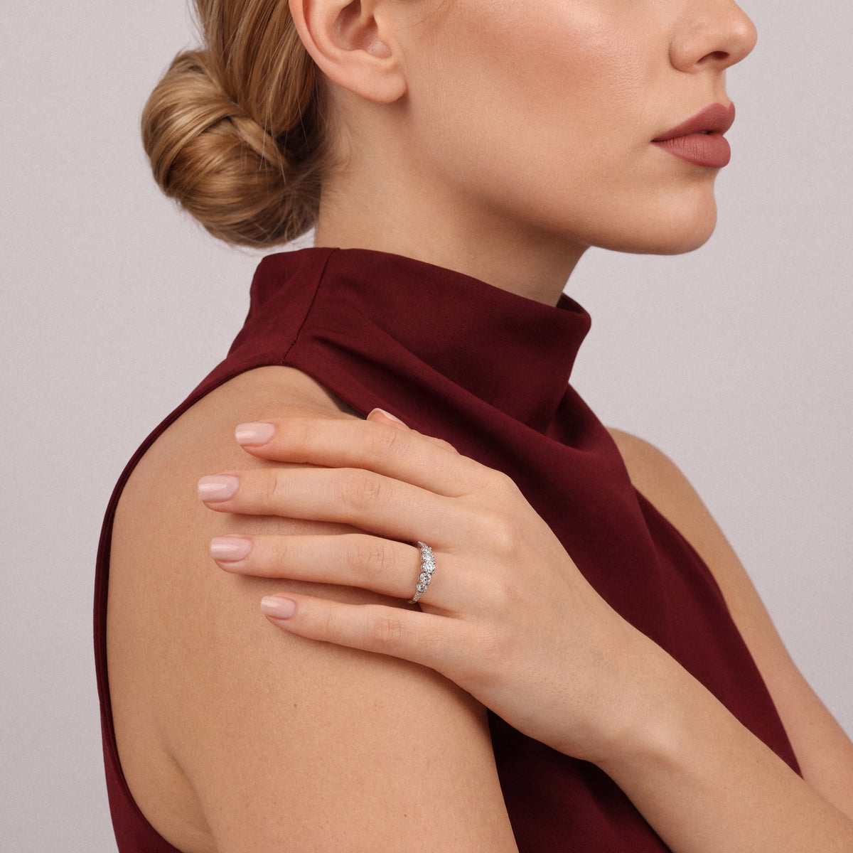 0.78 ct natural diamond five-stone ring in 14K white gold worn on the ring finger, hand resting on an oxblood silk shoulder