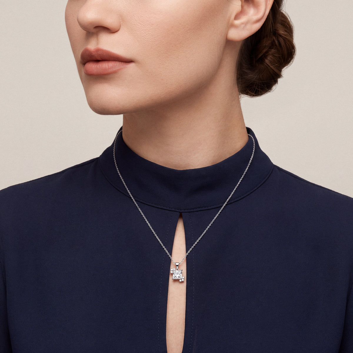 Woman in a midnight-navy mock-neck top wearing a princess-cut natural diamond solitaire pendant necklace in 14K white gold
