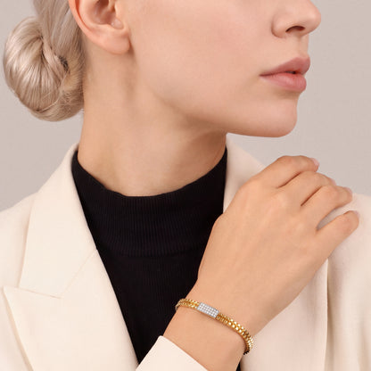 Woman in an ivory blazer wearing a natural diamond pavé bar hinged bangle in 14K yellow and white gold