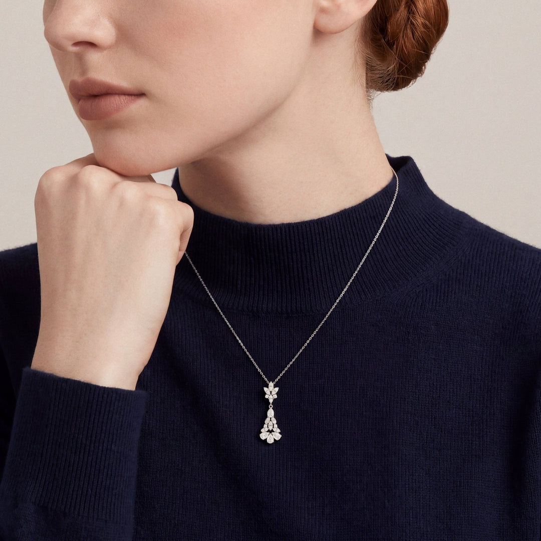Woman in a navy cashmere mock-neck top wearing a 0.77 ct tw natural diamond pear chandelier drop pendant necklace in 14K white gold