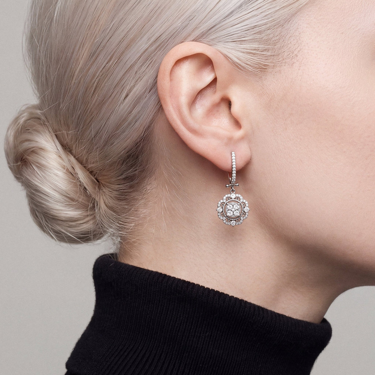 Woman in a black turtleneck wearing a 1.01 ct tw natural diamond flower halo drop earring in 14K white gold, side profile.