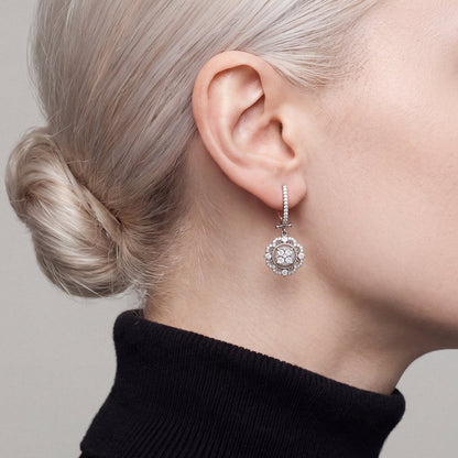 Woman in a black turtleneck wearing a 1.01 ct tw natural diamond flower halo drop earring in 14K white gold, side profile.