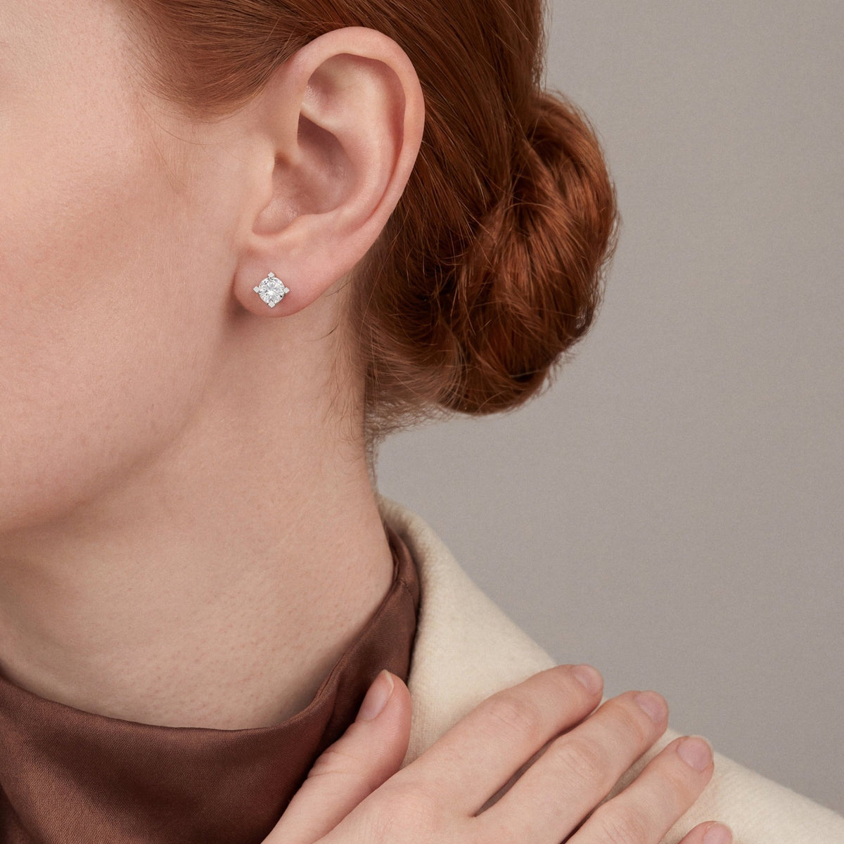 Model in a cream blazer over a chocolate high neck wearing a natural diamond four-prong solitaire stud earring in 14K white gold