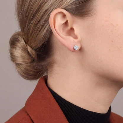 Model in a rust blazer over a black high neck wearing a natural diamond four-prong solitaire stud earring in 14K white gold