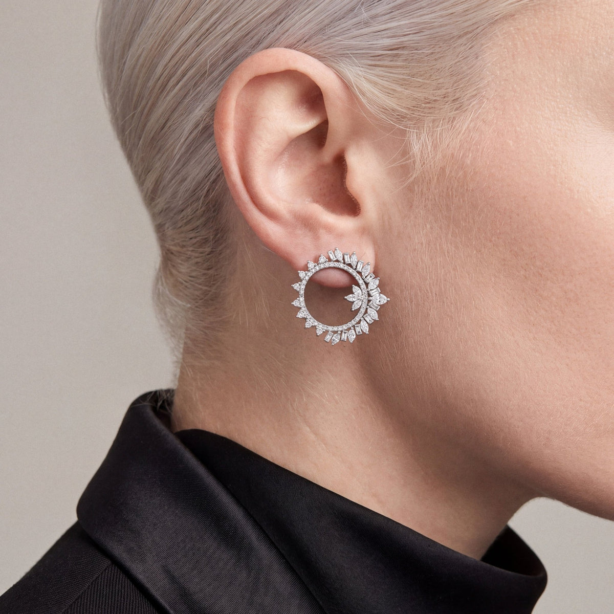 Woman in a black tuxedo jacket wearing a 2.43 ct tw natural diamond marquise and baguette open circle earring in 14K white gold.