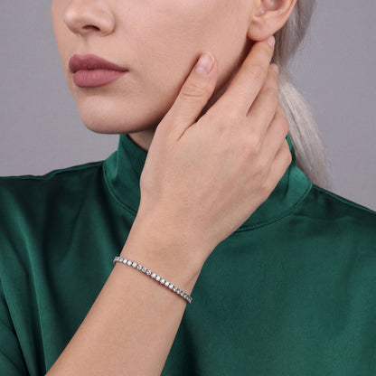 Woman in an emerald silk mock-neck top wearing a 6.68 ct tw natural diamond tennis bracelet in 14K white gold