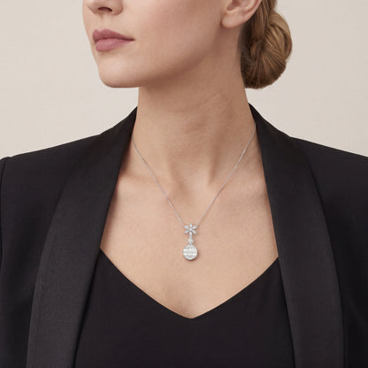 Woman in a black tuxedo jacket wearing the baguette natural diamond flower drop pendant necklace in 14K white gold