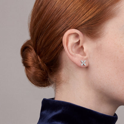 Woman in a navy velvet funnel-neck top wearing a baguette natural diamond flower stud earring in 14K white gold, side profile