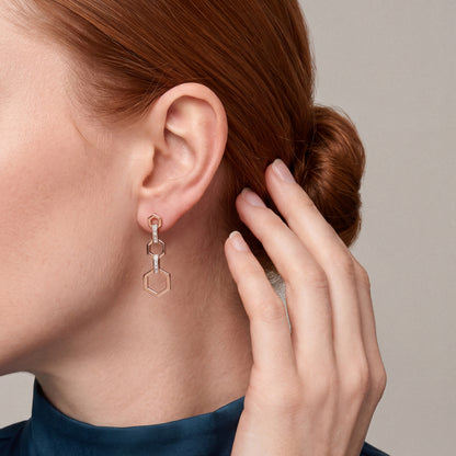 Model in a teal silk high-neck blouse with her hand in her hair, wearing a baguette natural diamond hexagon drop earring in 14K rose gold
