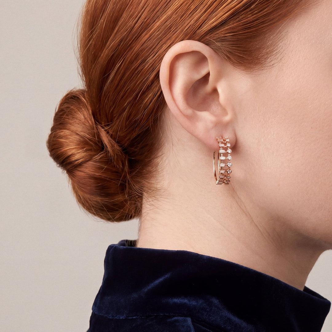 Model in a navy velvet stand-collar top, turned away, wearing a baguette and round natural diamond ladder hoop earring in 14K rose gold