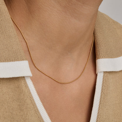 Woman wearing the 1 mm Ball Chain Necklace in gold — dainty everyday bead chain.