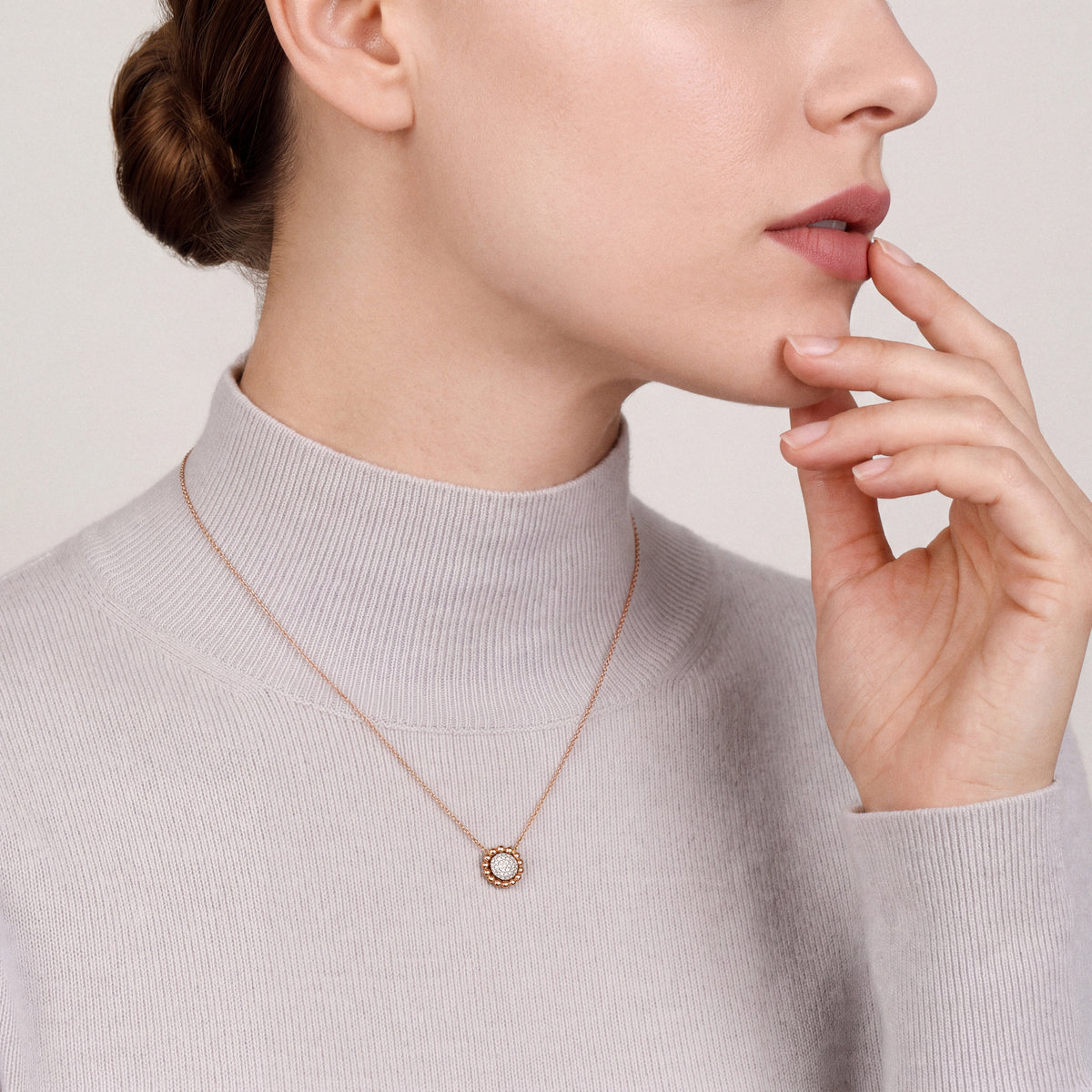 Model in a dove-grey cashmere high-neck top wearing a 0.13 ct natural diamond pavé disc pendant necklace in 14K rose and white gold