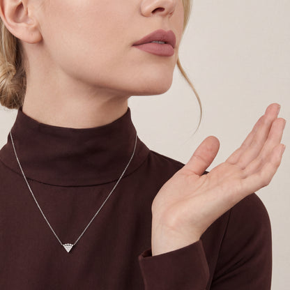 Woman in a chocolate-brown silk-crepe mock-neck top wearing a 0.12 ct natural diamond triangle necklace in 14K white gold.