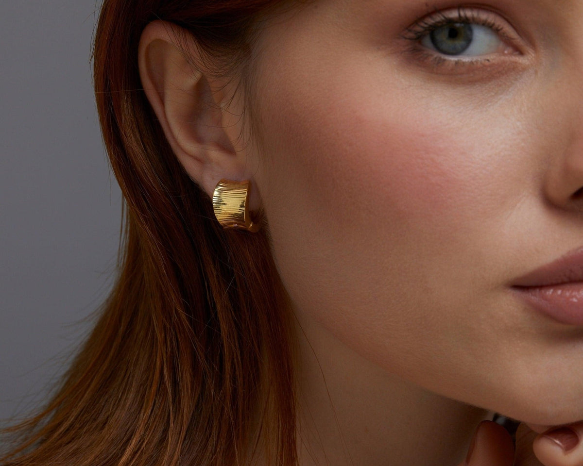 The Bold Huggie Hoop Earring styled in 18K Gold Vermeil — elegant everyday jewelry. Hypoallergenic for sensitive ears.