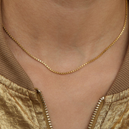 Close view of the Box Chain Necklace on the neck — 1.3 mm square links in gold.