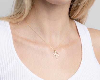 The Clover Heart Necklace in 14K solid gold on a model in a white ribbed tank top.