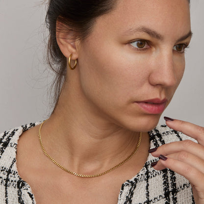 Gold curb chain necklace worn on the neck