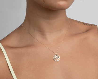 Close view of the 14K solid gold tree of life pendant resting just below the collarbone.