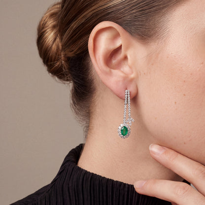 Emerald and natural diamond halo drop earring in 18K white gold, worn with a black pleated high neck