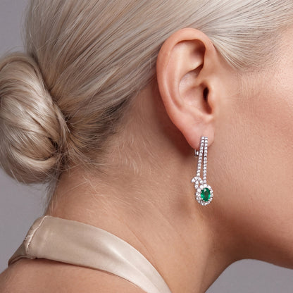 2.66 ct emerald and diamond drop earring in 18K white gold with a hinged lever-back, worn with a champagne silk halter