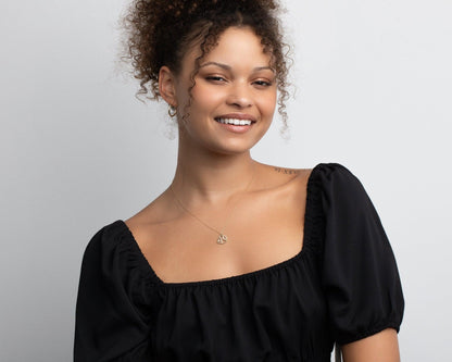 The 14K solid gold fish necklace on a model, the pendant resting just below the collarbone.