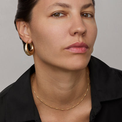 Gold flat link chain necklace worn on the neck
