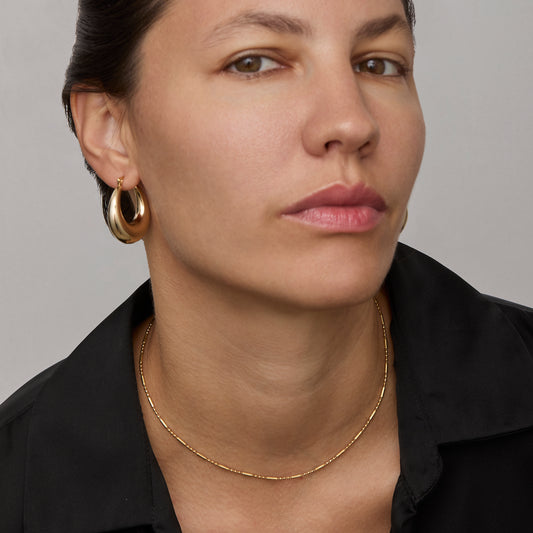 Gold flat link chain necklace worn on the neck