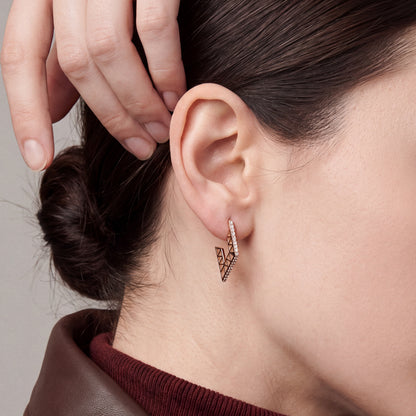 Model in a brown leather jacket tucking her hair behind her ear, wearing a geometric openwork natural diamond hoop earring in 14K rose gold