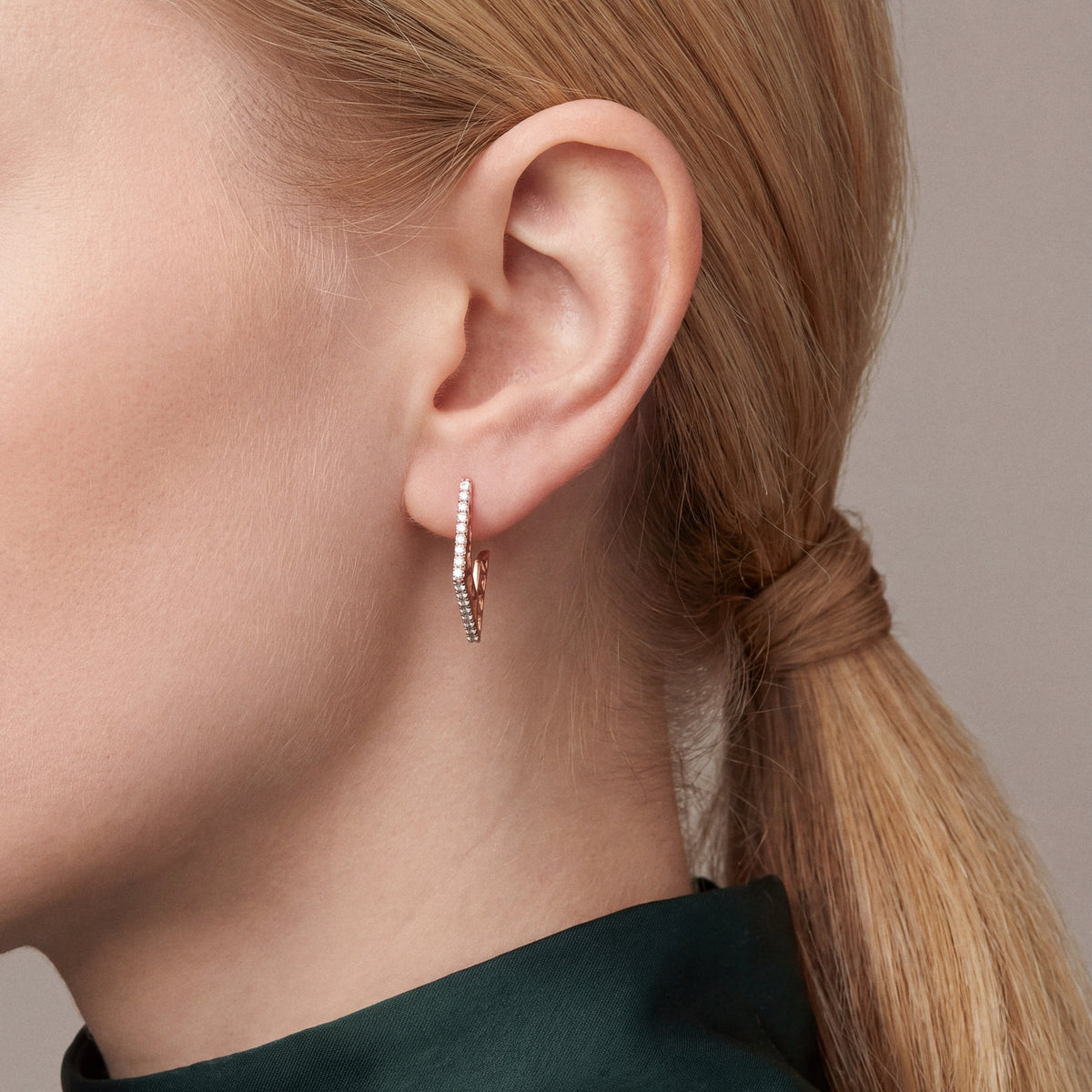 Model in an emerald silk shirt in profile wearing a geometric natural diamond hoop earring in 14K rose gold