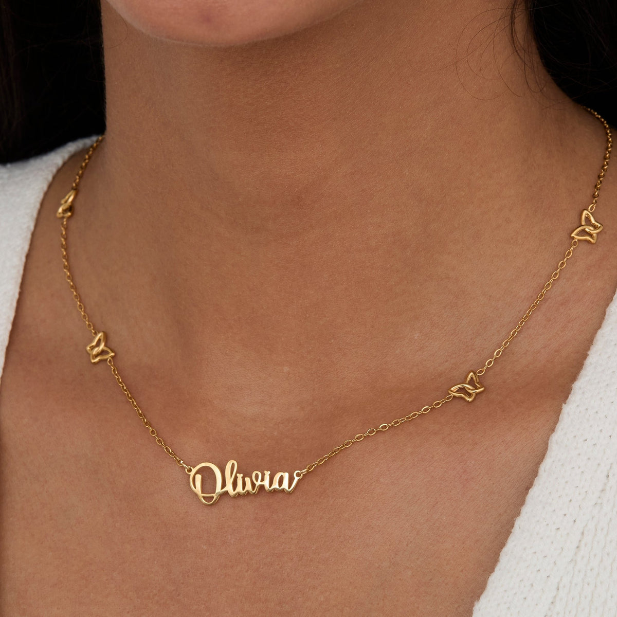 Close-up of the Gold Butterfly Name Necklace — script nameplate with butterfly charms along the chain.