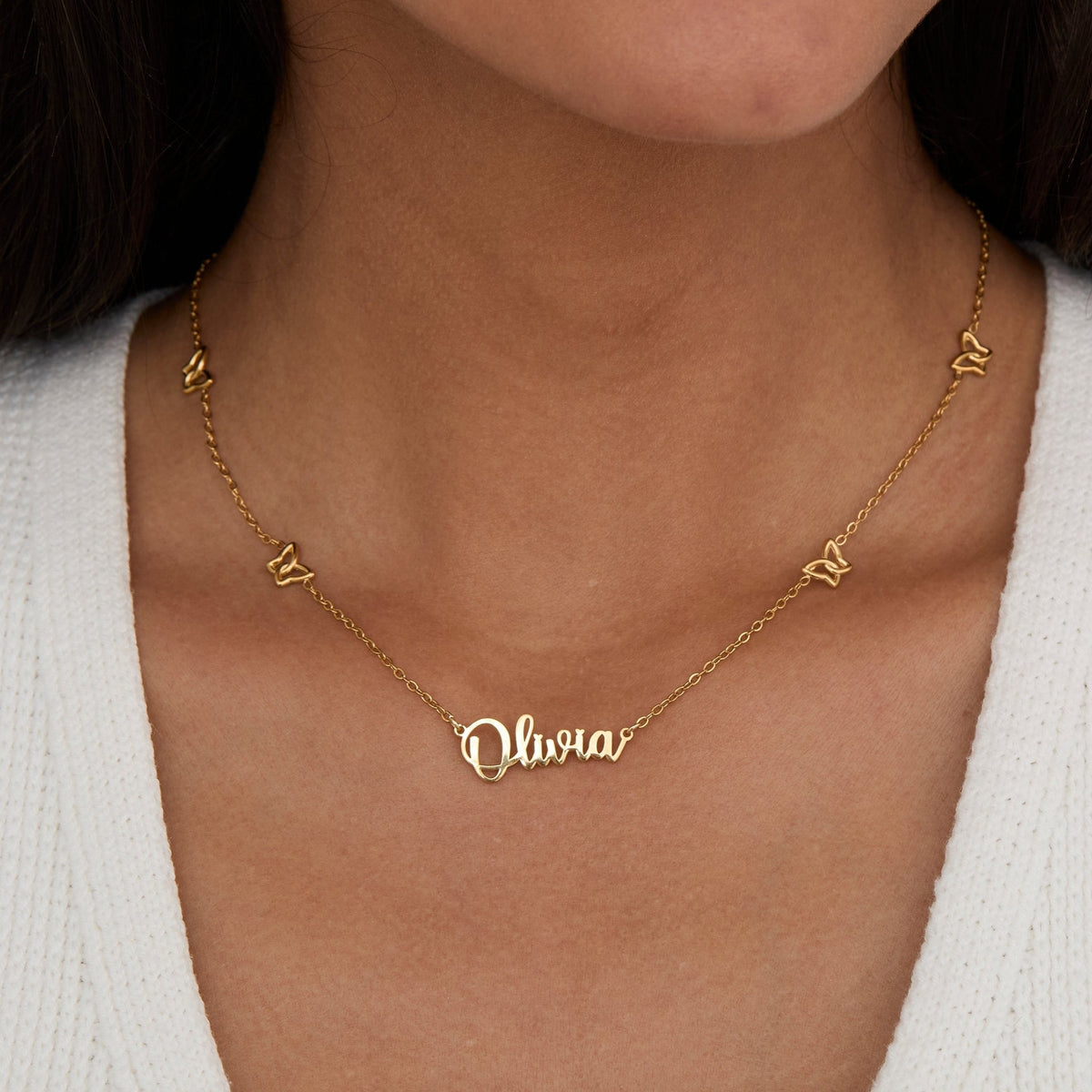 Gold Butterfly Name Necklace on the neckline — custom script name necklace with four butterflies.