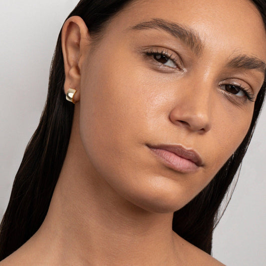 Close detail of the Gold Huggie Hoop Earrings in Gold-Plated Steel. Tarnish-resistant, premium handmade jewelry.