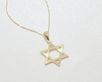 The 14K solid gold Star of David pendant on its chain, lying flat on a light background.