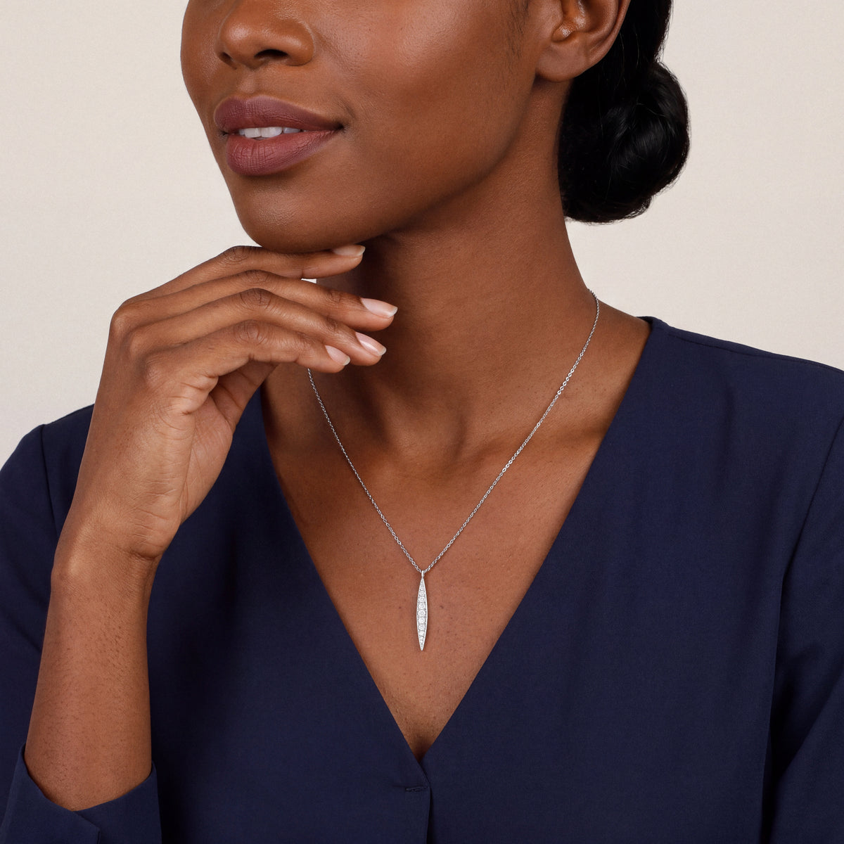 Woman in a navy blouse wearing the graduated natural diamond bar pendant necklace in 14K white gold