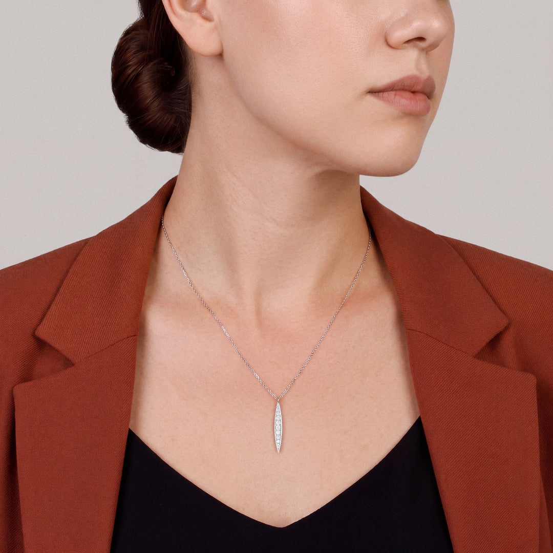 Woman in a rust blazer wearing the graduated natural diamond bar pendant necklace in 14K white gold