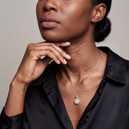 Model wearing the round diamond cluster halo pendant necklace in 14K white gold with a black silk blouse