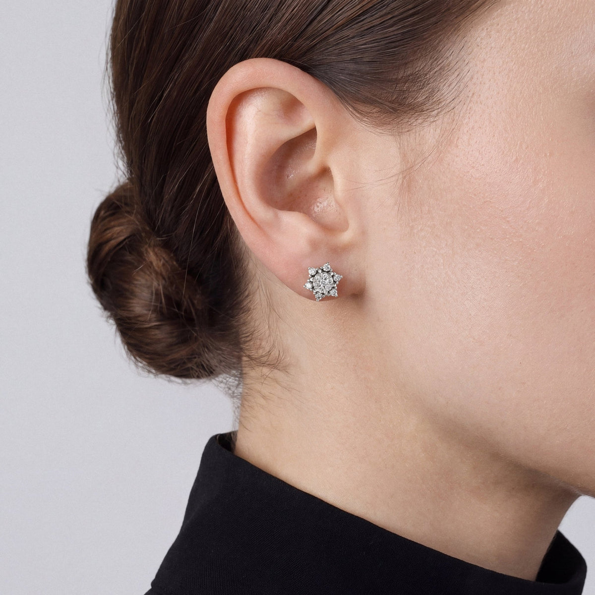 Woman in a black band-collar blouse wearing a lotus natural diamond cluster stud earring in 14K white gold, side profile