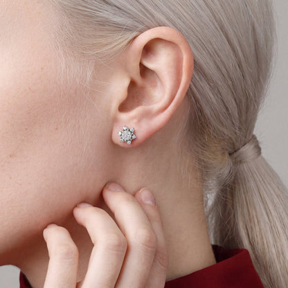 Woman in a crimson high-neck top with her fingertips at her jaw, wearing a lotus natural diamond cluster stud earring in 14K white gold