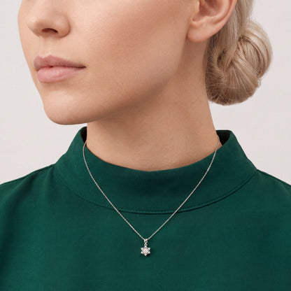 Woman in an emerald silk funnel-collar top wearing a 0.30 ct natural diamond lotus star pendant necklace in 14K white gold.