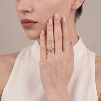 Woman in an ivory high-collar top wearing a marquise natural diamond leaf wrap ring in 14K rose gold on the ring finger, palm resting on her cheek