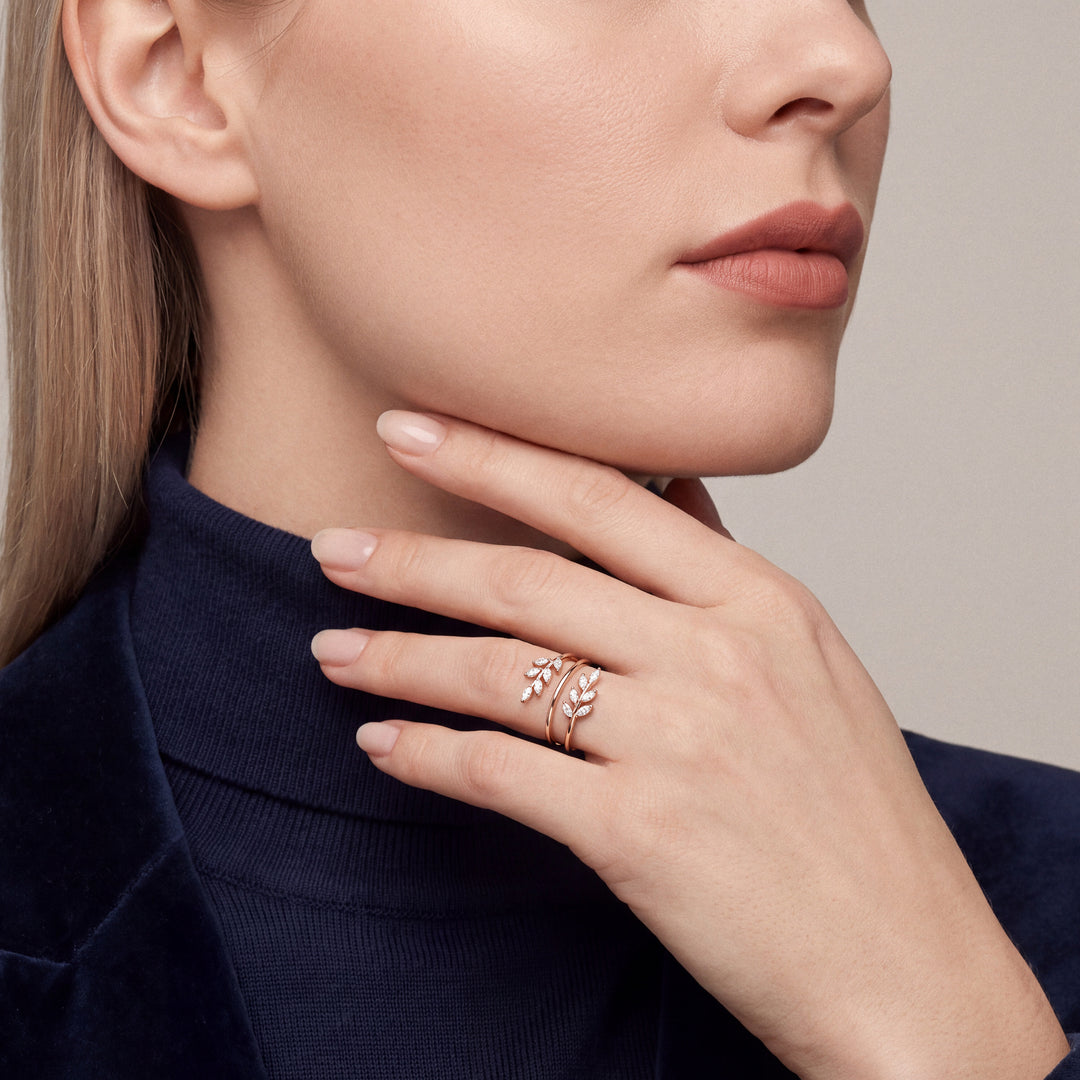 Marquise natural diamond leaf wrap ring in 14K rose gold worn on the ring finger, hand along the jaw over a navy turtleneck
