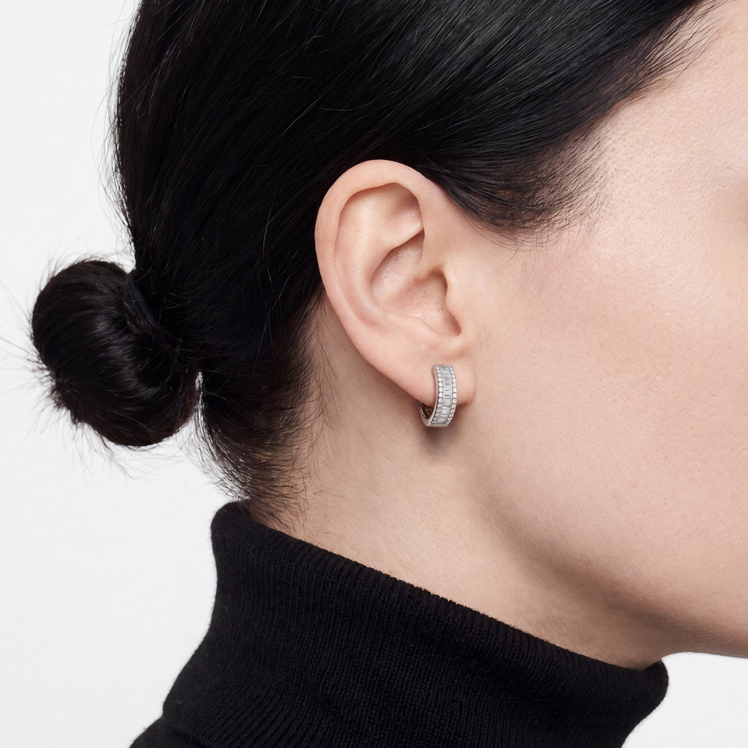 Second model in profile wearing the baguette and pave diamond huggie hoop earring